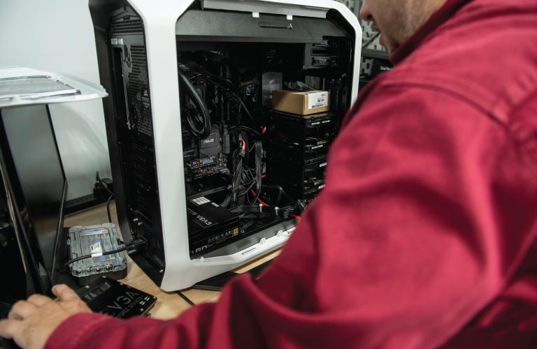 A Hi-Tech computer repair specialist prepares to replace broken graphics card in open PC tower case