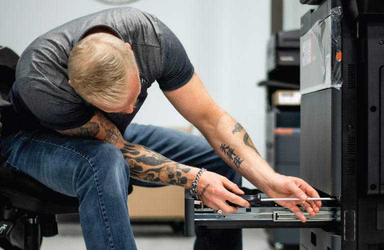 Photocopier technician uses screwdriver to disassemble and inspect Toshiba copier