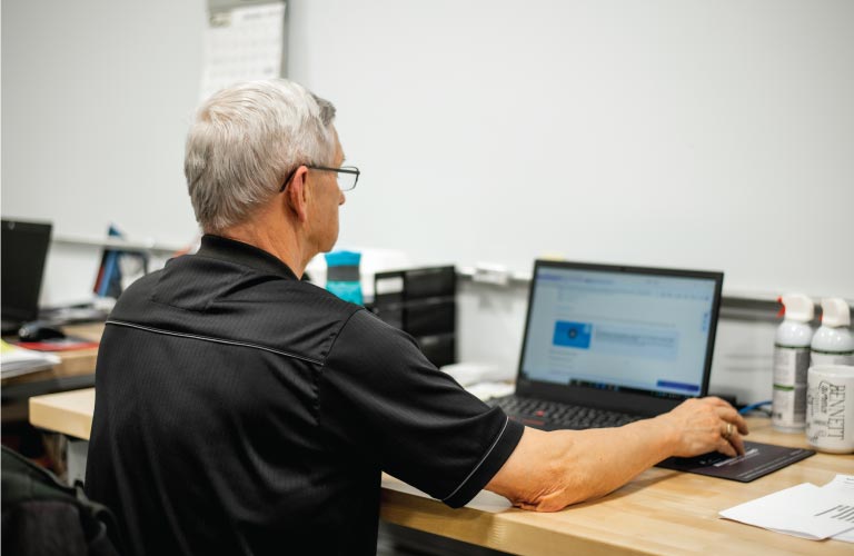 Computer technician inspects and troubleshoots software on laptop at IT service bench at Hi-Tech